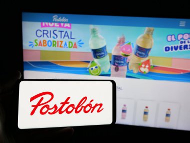 Stuttgart, Almanya - 05-05-2025: İnternet sitesinin önünde üzerinde Kolombiyalı içecek şirketi Postobon S.A. 'nın logosu olan akıllı telefon tutan kişi. Telefon ekranına odaklan.