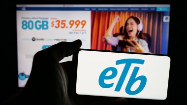 Stuttgart, Almanya - 05-05-2025: İnternet sayfasının önünde ekranda Empresa de Telecomunicaciones de Bogota (ETB) logosu bulunan kişi. Telefon ekranına odaklan.