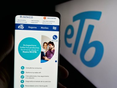 Stuttgart, Almanya - 05-05-2025: Logonun önünde Empresa de Telecomunicaciones de Bogota (ETB) logosunun logosu bulunan kişi. Telefon ekranının merkezine odaklan.