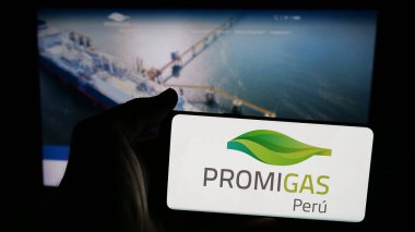 Stuttgart, Almanya - 05-05-2025: Kolombiyalı enerji şirketi Promigas S.A. 'nın logosuna sahip cep telefonu sahibi kişi Web sayfasının önünde ekranda. Telefon ekranına odaklan.