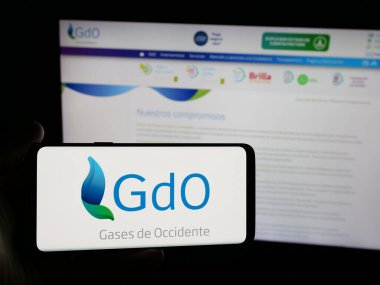 Stuttgart, Almanya - 05-05-2025: İnternet sitesinin önünde ekranda Gases de Occidente S.A. adlı enerji şirketinin logosunun bulunduğu akıllı telefonu tutan kişi. Telefon ekranına odaklan.