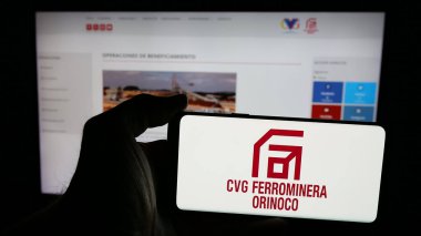 Stuttgart, Almanya - 05-06-2025: Maden şirketi CVG Ferrominera Orinoco C.A. logosu olan cep telefonu sahibi kişi Web sayfasının önünde ekranda. Telefon ekranına odaklan.