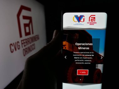 Stuttgart, Almanya - 05-06-2025: Maden şirketi CVG Ferrominera Orinoco C.A. 'nın internet sayfası ile cep telefonu tutan kişi Ekranda logonun önünde. Telefon ekranının merkezine odaklan.