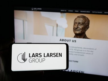 Stuttgart, Almanya - 05-06-2025: Web sitesi önünde üzerinde yatırım şirketi Lars Larsen Group AS logosu bulunan akıllı telefon sahibi kişi. Telefon ekranına odaklan.