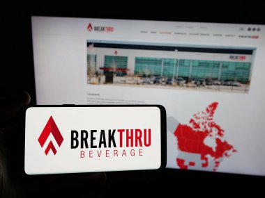 Stuttgart, Almanya - 05-06-2025: ABD 'li Breakthru Beverage Group LLC logosuna sahip akıllı telefon sahibi kişi web sitesi önünde ekranda. Telefon ekranına odaklan.