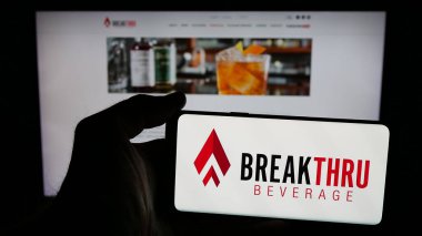 Stuttgart, Almanya - 05-06-2025: ABD 'li Breakthru Beverage Group LLC logosuna sahip cep telefonu sahibi kişi web sayfası önünde ekranda. Telefon ekranına odaklan.