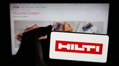 Stuttgart, Almanya - 05-06-2025: İnternet sayfasının önündeki ekranda üzerinde elektrikli alet şirketi Hilti AG logosu bulunan cep telefonu sahibi kişi. Telefon ekranına odaklan.