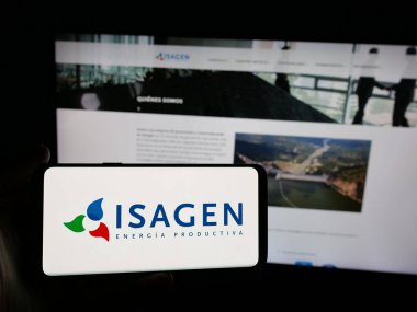 Stuttgart, Almanya - 05-06-2025: Kolombiyalı enerji şirketi Isagen S.A. 'nın logosuna sahip akıllı telefon sahibi kişi. Web sitesinin önünde ekranda. Telefon ekranına odaklan.