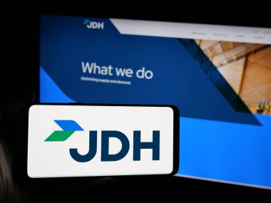 Stuttgart, Almanya - 05-07-2025: ABD 'li J.D. şirketinin logosuna sahip akıllı telefon sahibi kişi Heiskell Holding LLLC (JDH) web sitesinin önünde ekranda. Telefon ekranına odaklan.