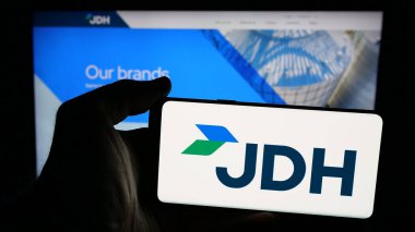 Stuttgart, Almanya - 05-07-2025: ABD 'li J.D. şirketinin logosuna sahip cep telefonu sahibi kişi Heiskell Holding LLLC (JDH) web sayfasının önünde ekranda. Telefon ekranına odaklan.