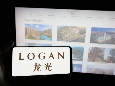 Stuttgart, Almanya - 05-07-2025: Çinli Logan Group Limited şirketinin logosunu elinde tutan kişi web sitesinin önünde ekranda. Telefon ekranına odaklan.