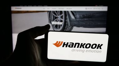 Stuttgart, Almanya - 05-07-2025: Hankook Tire Technology Co. Ltd şirketinin logosuna sahip cep telefonu sahibi kişi web sayfasının önünde ekranda. Telefon ekranına odaklan.