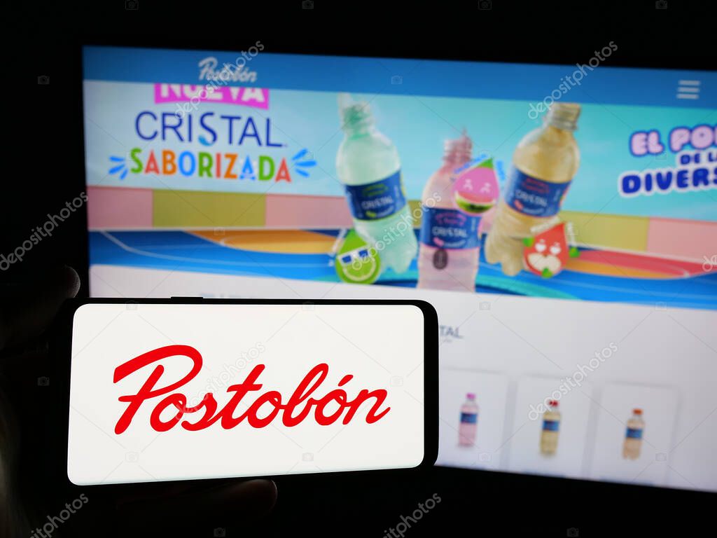 Stuttgart, Germany - 05-05-2025: Person holding smartphone with logo of Colombian beverage company Postobon S.A. on screen in front of website. Focus on phone display.