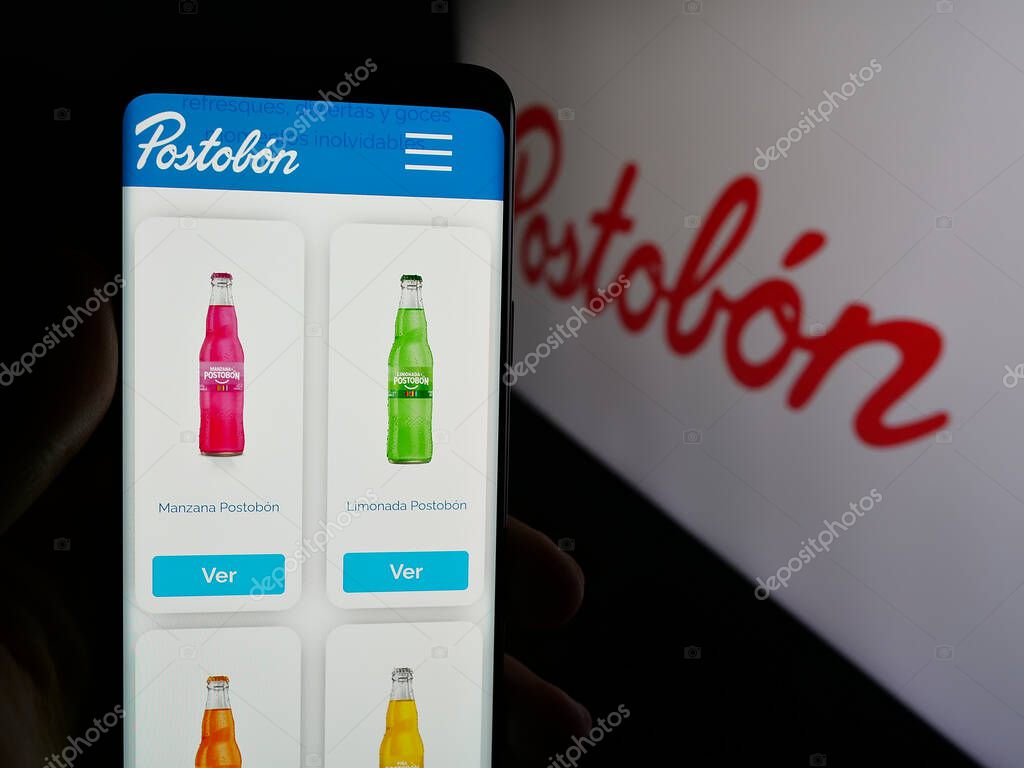Stuttgart, Germany - 05-05-2025: Person holding cellphone with webpage of Colombian beverage company Postobon S.A. on screen in front of logo. Focus on center of phone display.