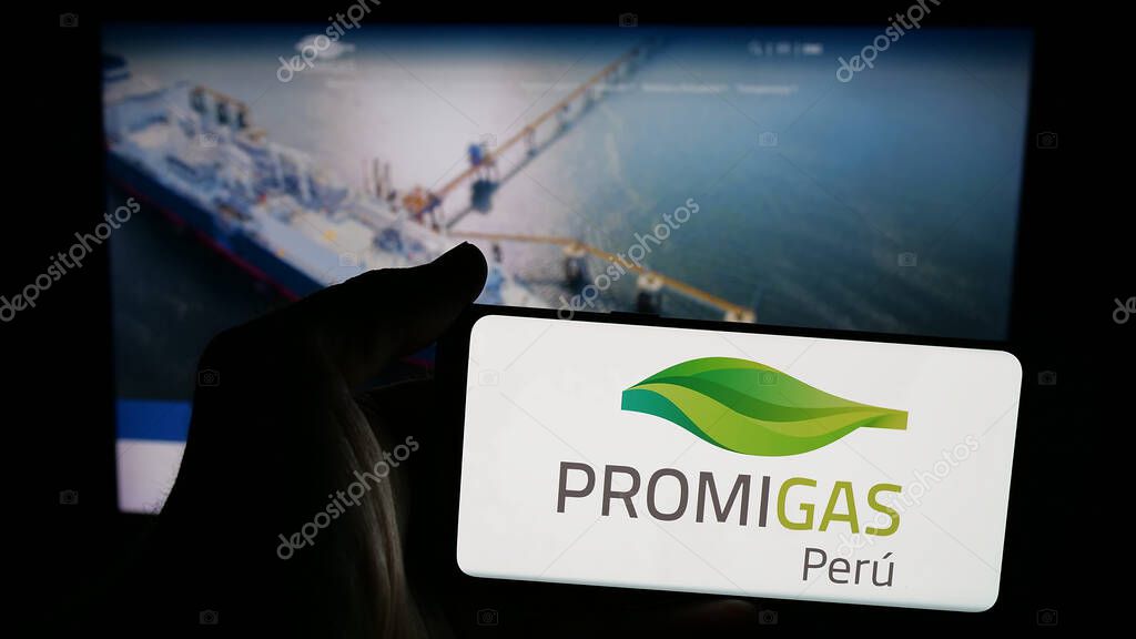 Stuttgart, Germany - 05-05-2025: Person holding mobile phone with logo of Colombian energy company Promigas S.A. E.S.P. on screen in front of web page. Focus on phone display.
