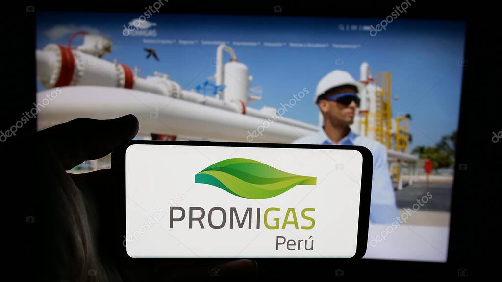 Stuttgart, Germany - 05-05-2025: Person holding cellphone with logo of Colombian energy company Promigas S.A. E.S.P. on screen in front of webpage. Focus on phone display.