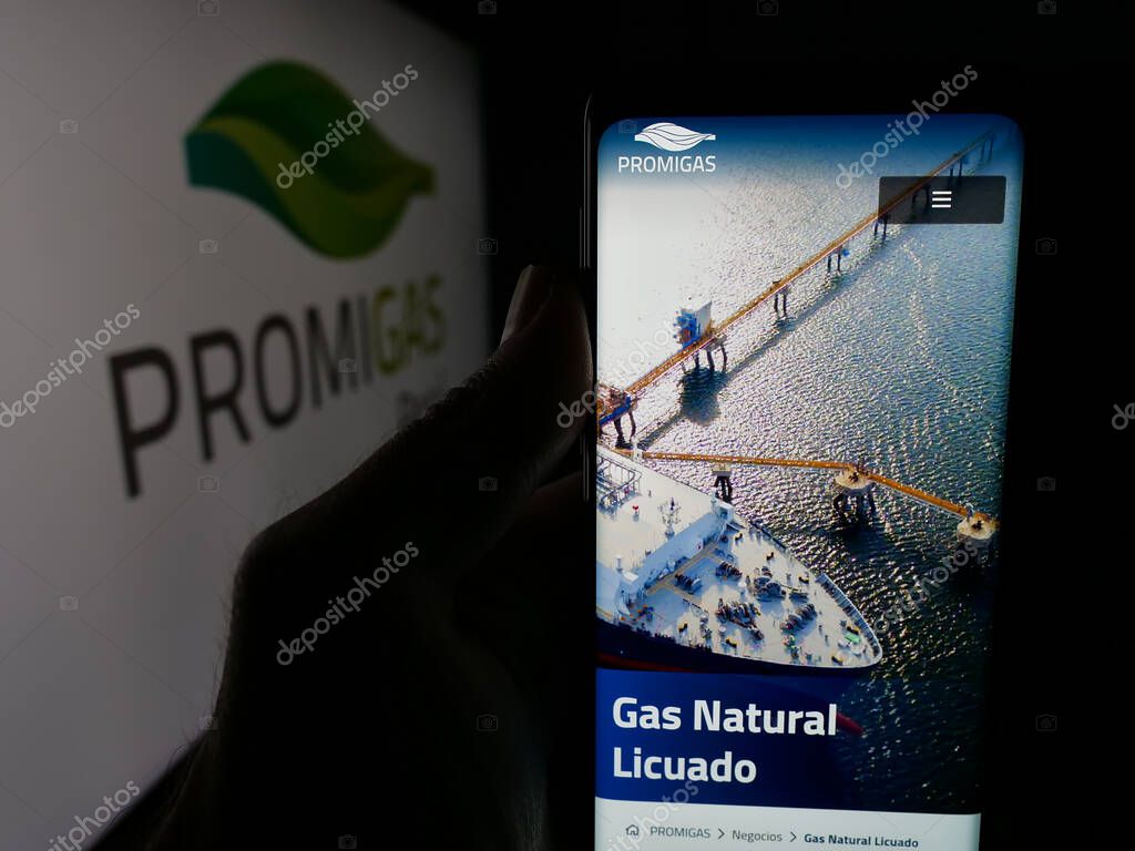 Stuttgart, Germany - 05-05-2025: Person holding cellphone with webpage of Colombian energy company Promigas S.A. E.S.P. on screen in front of logo. Focus on center of phone display.