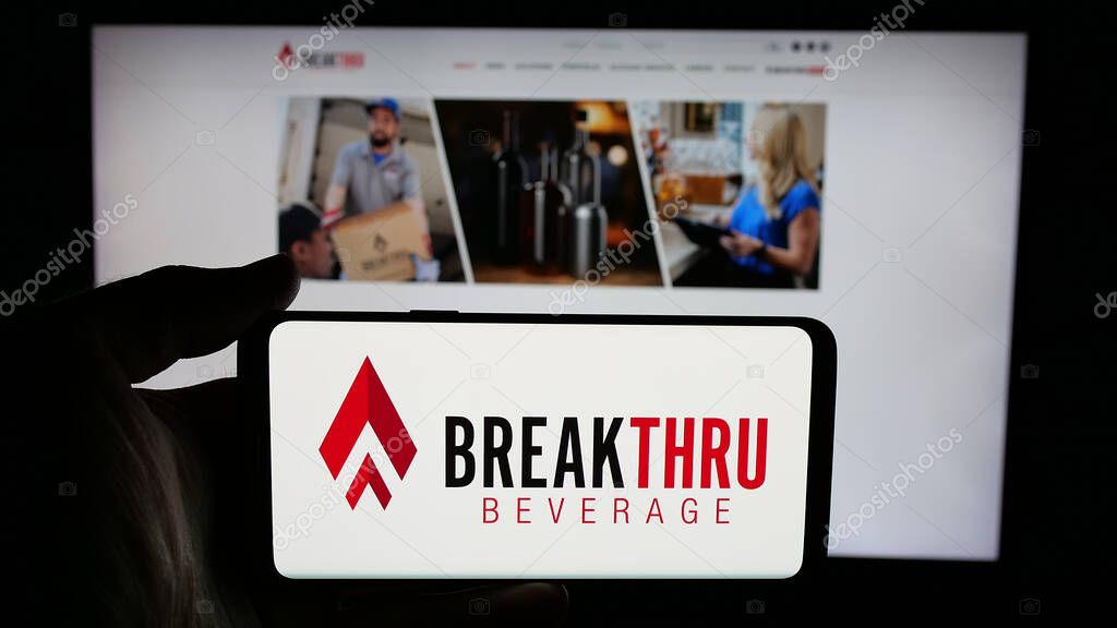 Stuttgart, Germany - 05-06-2025: Person holding cellphone with logo of US company Breakthru Beverage Group LLC on screen in front of webpage. Focus on phone display.