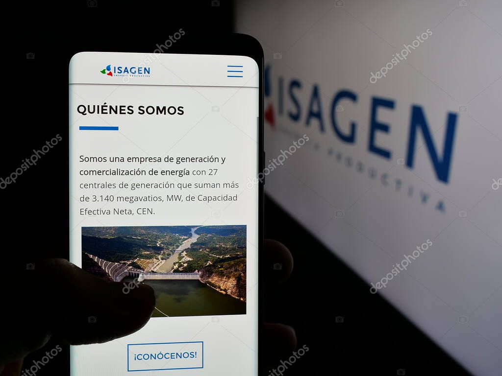 Stuttgart, Germany - 05-06-2025: Person holding cellphone with webpage of Colombian energy company Isagen S.A. E.S.P. on screen in front of logo. Focus on center of phone display.