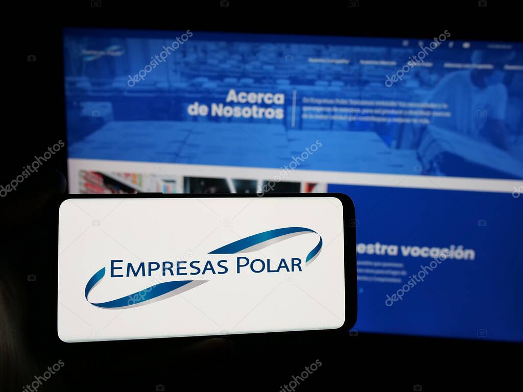 Stuttgart, Germany - 05-06-2025: Person holding smartphone with logo of Venezuelan beverage company Empresas Polar on screen in front of website. Focus on phone display.