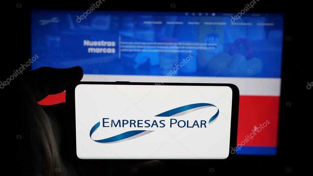 Stuttgart, Germany - 05-06-2025: Person holding cellphone with logo of Venezuelan beverage company Empresas Polar on screen in front of webpage. Focus on phone display.