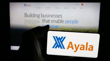 Stuttgart, Almanya - 05-14-2025: Filipinli holding şirketi Ayala Corporation 'ın logosuna sahip cep telefonu sahibi kişi web sayfasının önünde ekranda. Telefon ekranına odaklan.