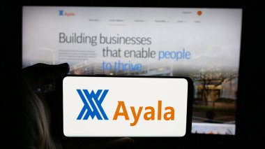 Stuttgart, Almanya - 05-14-2025: Filipinli holding şirketi Ayala Corporation 'ın logosunu elinde tutan kişi web sayfasının önünde ekranda. Telefon ekranına odaklan.