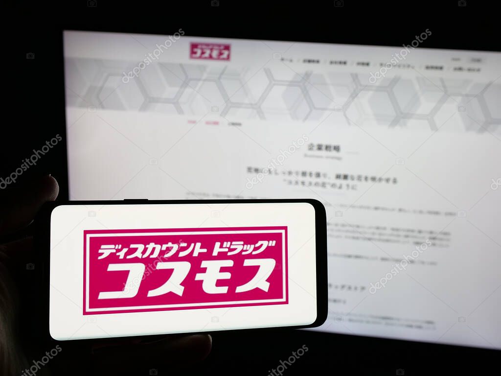 Stuttgart, Germany - 05-14-2025: Person holding smartphone with logo of Japanese company COSMOS Pharmaceutical Corp. on screen in front of website. Focus on phone display.