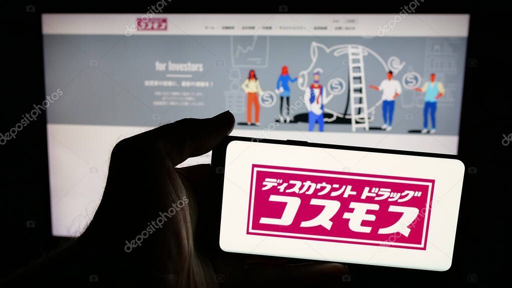 Stuttgart, Germany - 05-14-2025: Person holding mobile phone with logo of Japanese company COSMOS Pharmaceutical Corp. on screen in front of web page. Focus on phone display.