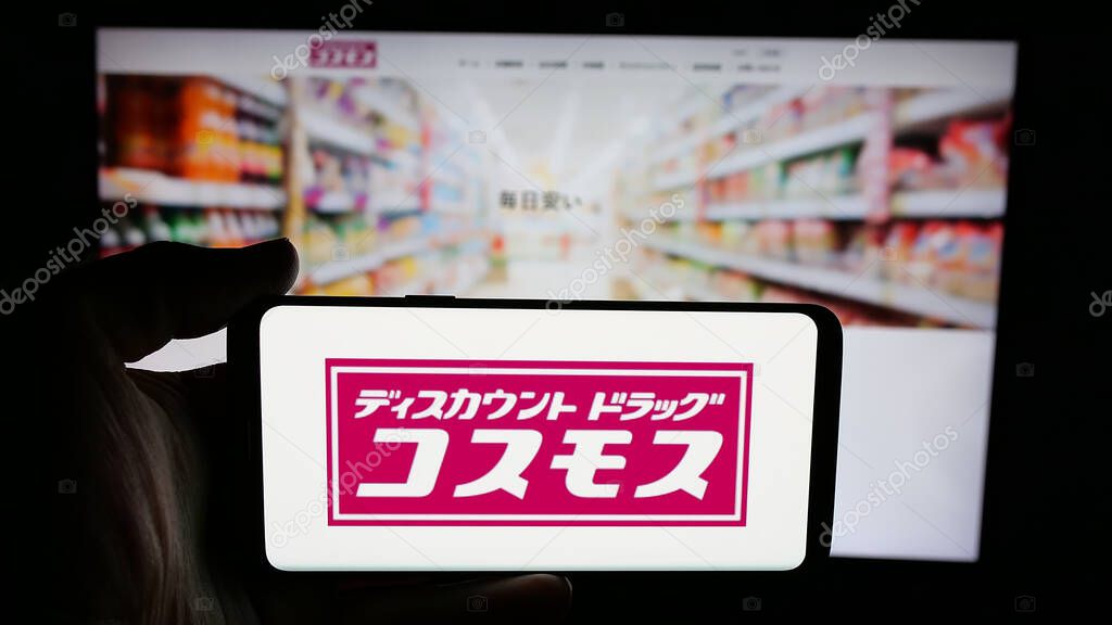 Stuttgart, Germany - 05-14-2025: Person holding cellphone with logo of Japanese company COSMOS Pharmaceutical Corp. on screen in front of webpage. Focus on phone display.