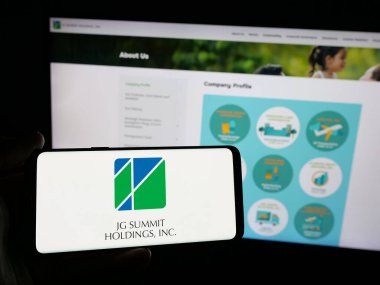 Stuttgart, Almanya - 05-14-2025: İnternet sitesi önünde JG Summit Holding Inc. (JGSHI) şirketinin logosuna sahip akıllı telefon sahibi kişi. Telefon ekranına odaklan.