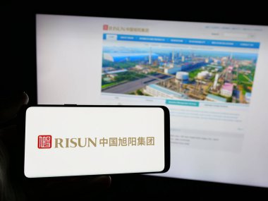 Stuttgart, Almanya - 05-14-2025: Kokain şirketi China Risun Group Limited 'in logosuna sahip akıllı telefon sahibi kişi web sitesinin önünde ekranda. Telefon ekranına odaklan.