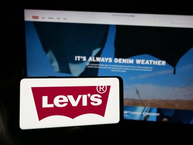 Stuttgart, Almanya - 05-14-2025: İnternet sitesi önünde üzerinde ABD 'li giyim şirketi Levi Strauss Co. (Levi' s) logosu bulunan kişi. Telefon ekranına odaklan.