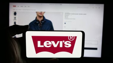 Stuttgart, Almanya - 05-14-2025: İnternet sayfası önünde ABD 'li giyim şirketi Levi Strauss Co. (Levi' s) logosunun bulunduğu cep telefonu sahibi kişi. Telefon ekranına odaklan.