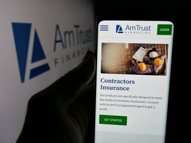 Stuttgart, Almanya - 05-15-2025: ABD 'li AmTrust Finansal Hizmetler Şirketi' nin web sayfası ile akıllı telefon sahibi kişi logonun önünde ekranda. Telefon ekranının merkezine odaklan.