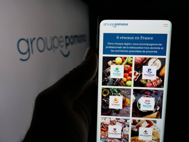 Stuttgart, Almanya - 05-15-2025: Gıda dağıtım şirketi Groupe Pomona 'nın web sayfası ile akıllı telefon taşıyan kişi logonun önünde ekranda. Telefon ekranının merkezine odaklan.