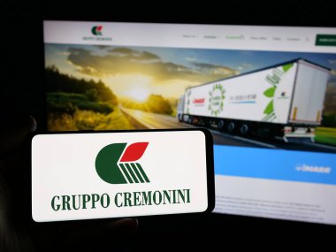 Stuttgart, Almanya - 05-15-2025: İnternet sitesinin önünde üzerinde et işleme şirketi Cremonini S.P.A. logosu olan akıllı telefon tutan kişi. Telefon ekranına odaklan.