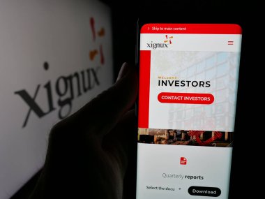 Stuttgart, Almanya - 05-15-2025: Meksika şirketi Xignux S.A. de C.V. 'nin web sayfası olan akıllı telefon sahibi kişi logonun önünde ekranda. Telefon ekranının merkezine odaklan.