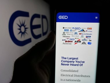Stuttgart, Almanya - 05-15-2025: Logo önündeki ekranda Consolidated Electrical Distributors (CED) web sayfası bulunan cep telefonu sahibi kişi. Telefon ekranının merkezine odaklan.
