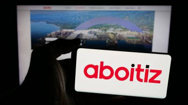 Stuttgart, Almanya - 05-15-2025: Web sayfası önünde üzerinde Aboitiz Equity Ventures Inc. (AEV) logosu olan cep telefonu sahibi kişi. Telefon ekranına odaklan.