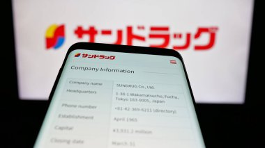 Stuttgart, Almanya - 05-16-2025: Eczacılık şirketi Sundrug Co. Ltd. 'nun web sitesiyle birlikte cep telefonu logonun önünde ekranda. Telefon ekranının sol üst kısmına odaklan.