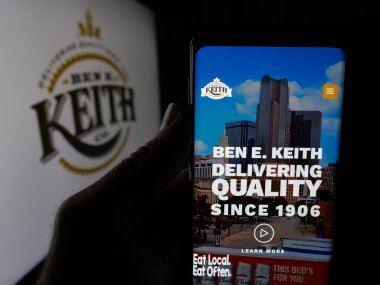 Stuttgart, Almanya - 05-16-2025: ABD dağıtım şirketi Ben E. Keith Company 'nin web sayfası olan akıllı telefon sahibi kişi logonun önünde ekranda. Telefon ekranının merkezine odaklan.