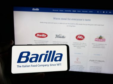 Stuttgart, Almanya - 05-16-2025: İtalyan gıda işleme şirketi Barilla 'nın logosunu elinde tutan kişi web sitesinin önünde ekranda. Telefon ekranına odaklan.