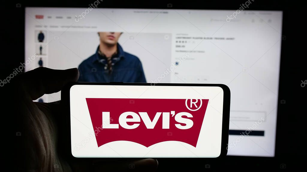 Stuttgart, Germany - 05-14-2025: Person holding cellphone with logo of US clothing company Levi Strauss Co. (Levi's) on screen in front of webpage. Focus on phone display.