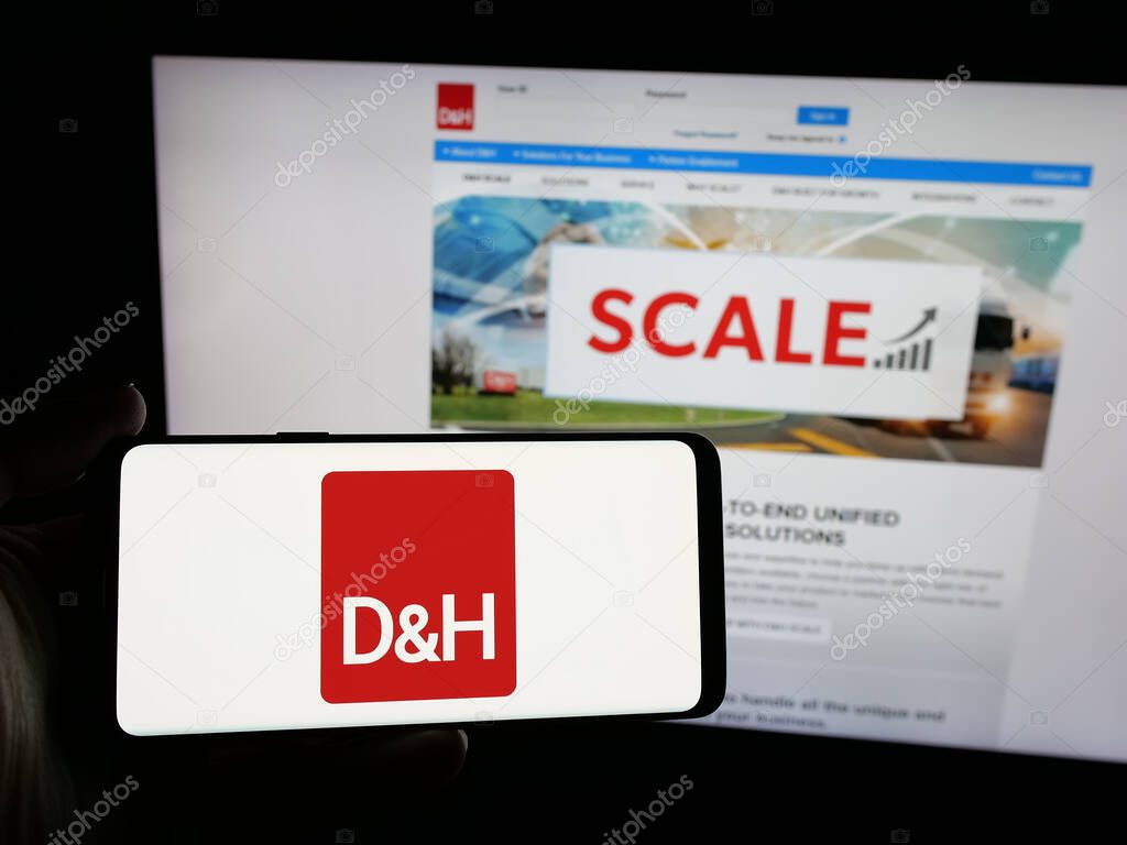 Stuttgart, Germany - 05-15-2025: Person holding smartphone with logo of IT distribution company DH Distributing Co. on screen in front of website. Focus on phone display.