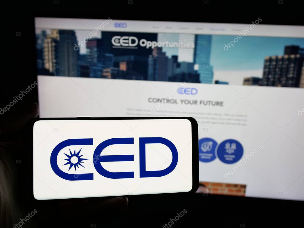 Stuttgart, Germany - 05-15-2025: Person holding smartphone with logo of Consolidated Electrical Distributors (CED) on screen in front of website. Focus on phone display.