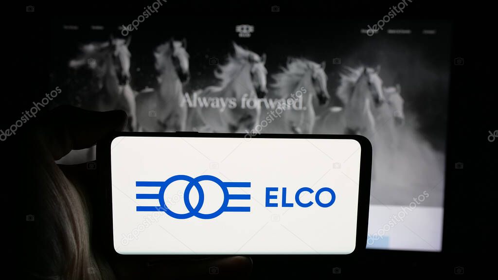 Stuttgart, Germany - 05-16-2025: Person holding mobile phone with logo of Israeli holding company Elco Ltd. on screen in front of web page. Focus on phone display.