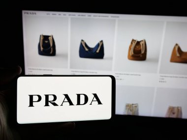 Stuttgart, Almanya - 05-17-2025: Lüks moda evi şirketi Prada S.P.A. 'nın logosuna sahip akıllı telefon sahibi kişi web sitesinin önünde ekranda. Telefon ekranına odaklan.