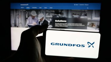 Stuttgart, Almanya - 05-17-2025: Pompa üretim şirketi Grundfos Group 'un logosunun bulunduğu cep telefonu web sayfasının önünde ekranda. Telefon ekranına odaklan.