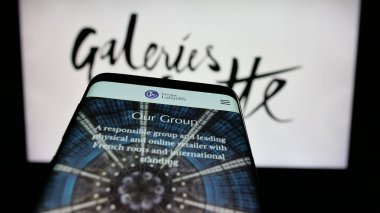 Stuttgart, Almanya - 05-17-2025: Alışveriş merkezi şirketi Galeries Lafayette 'in web sitesiyle birlikte logo önünde cep telefonu. Telefon ekranının sol üst kısmına odaklan.
